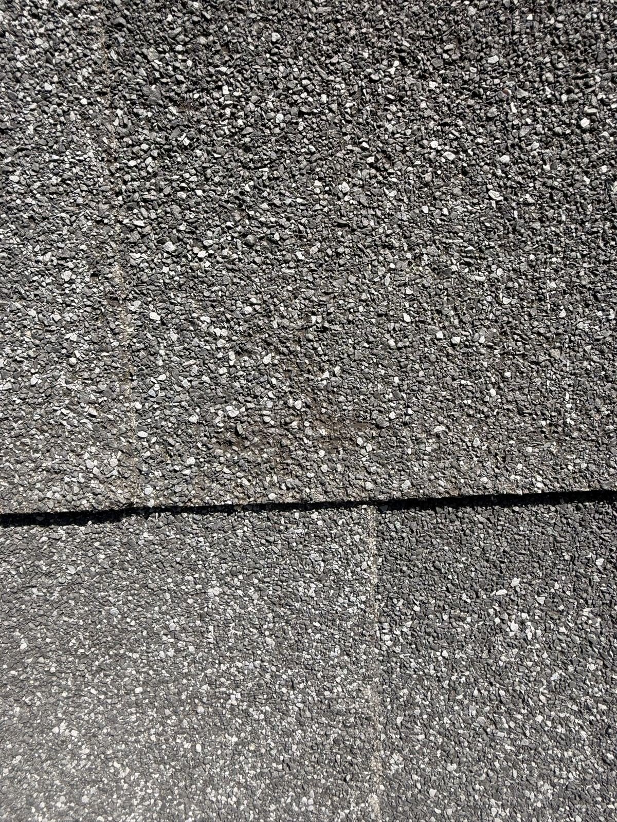 Close-up of hail bruising on a black asphalt shingle