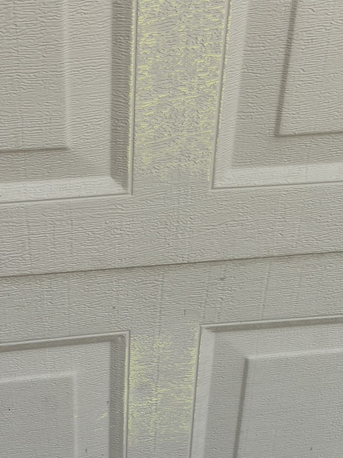 Hail dent and scuff mark on a garage door panel