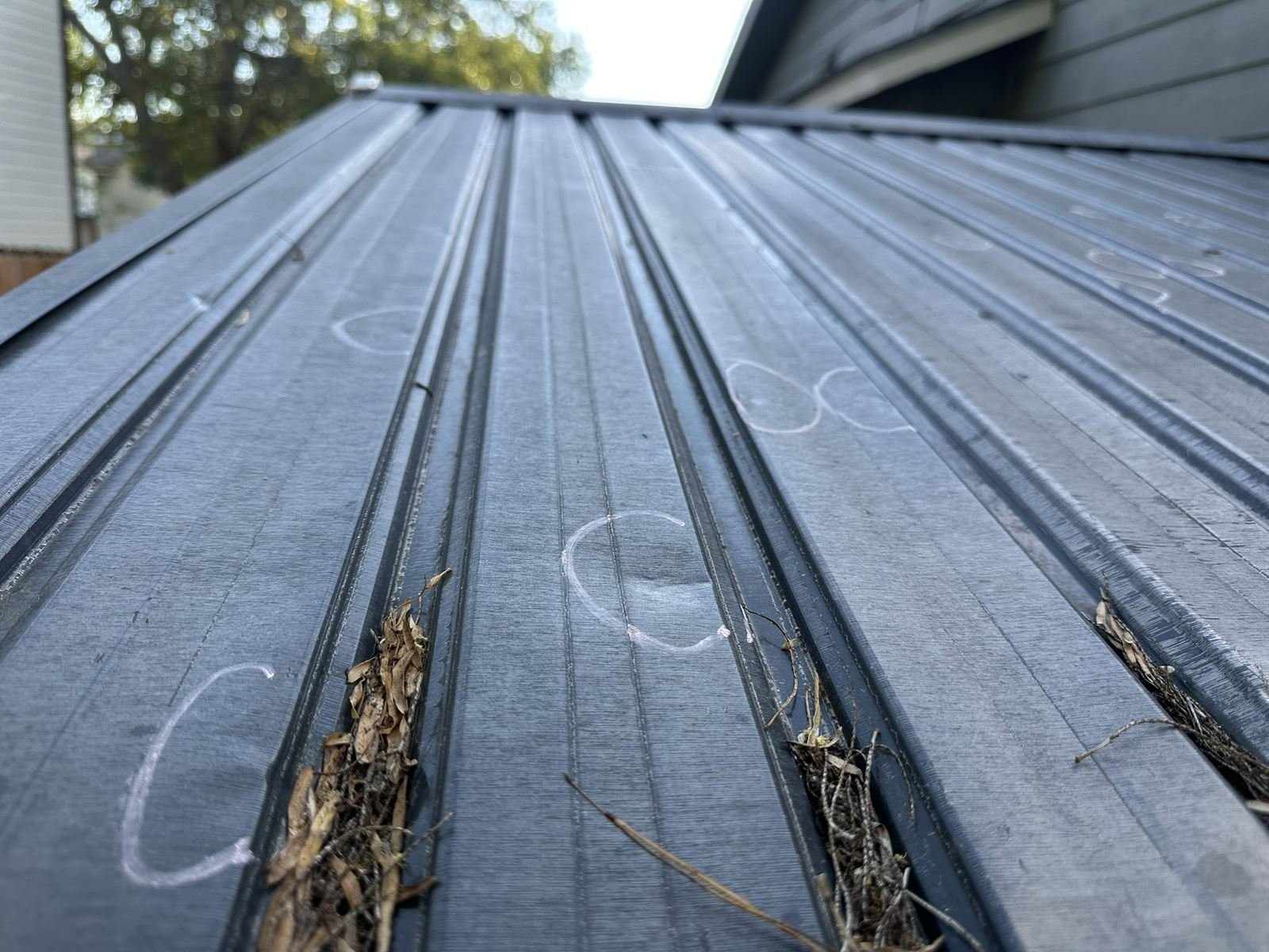 Chalk-marked hail hits on a shed's metal roof panel
