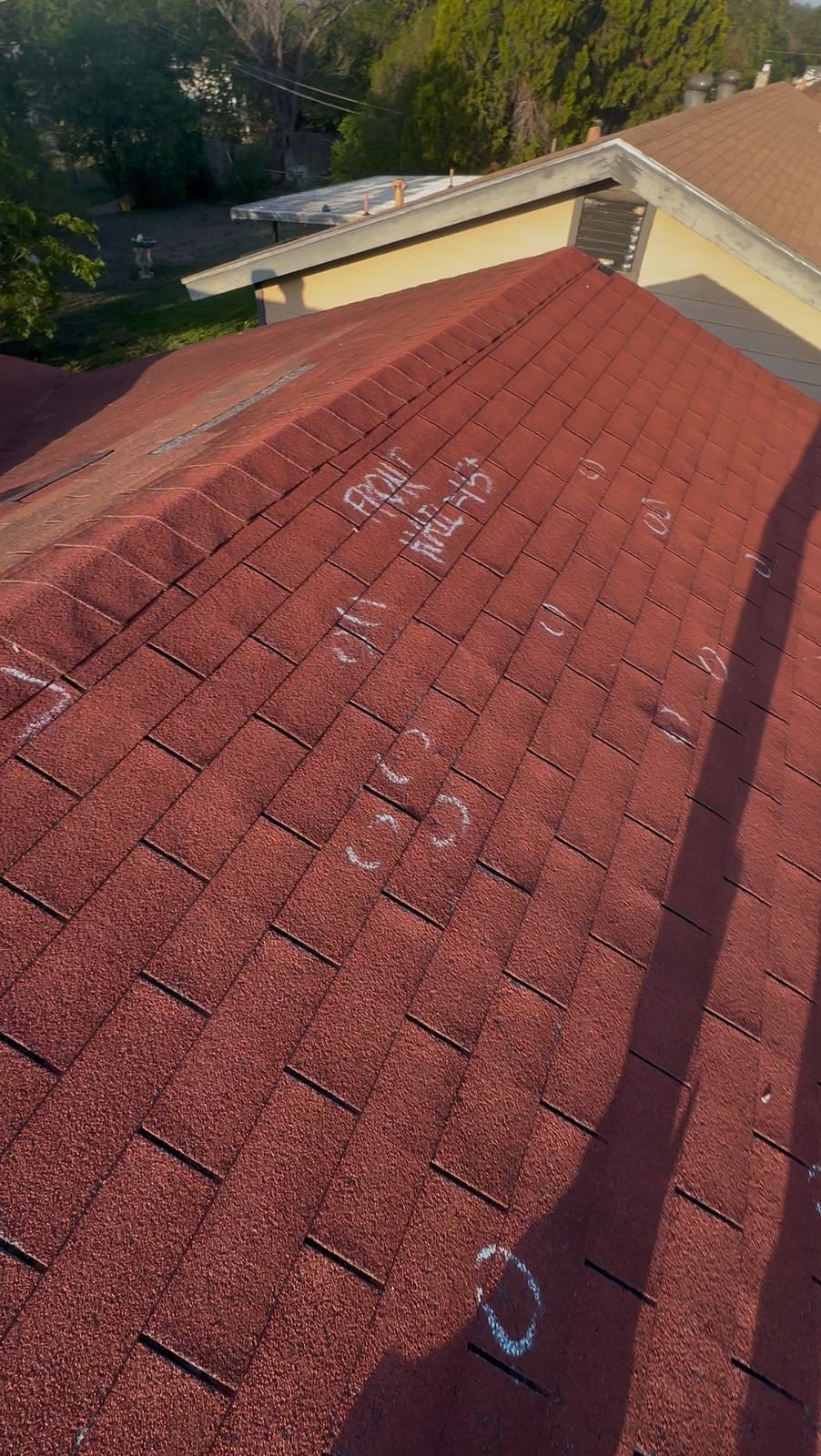 Aerial view of a shingle roof with chalk-marked hail hit counts