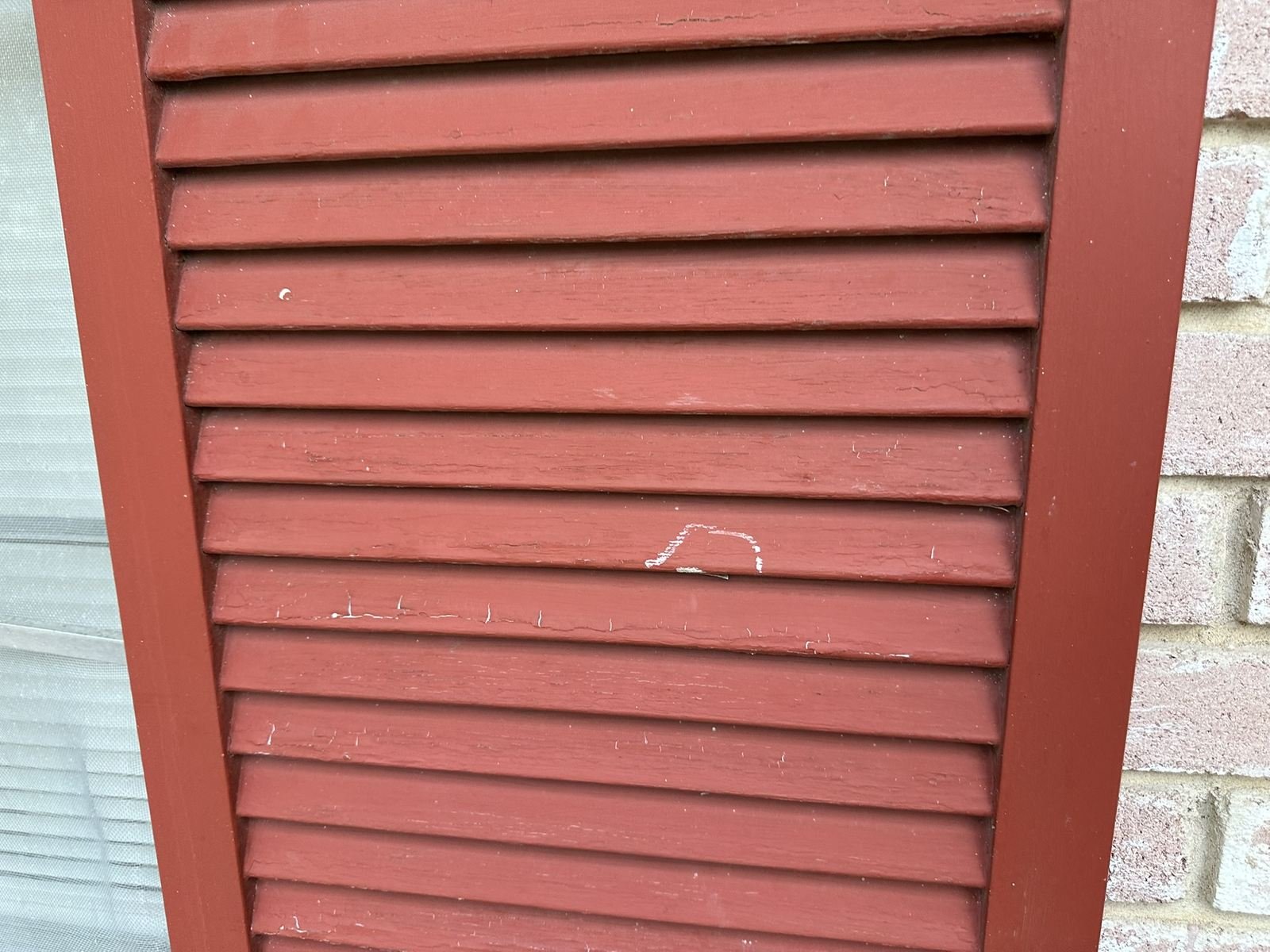 Hail impact mark chalked on an exterior shutter