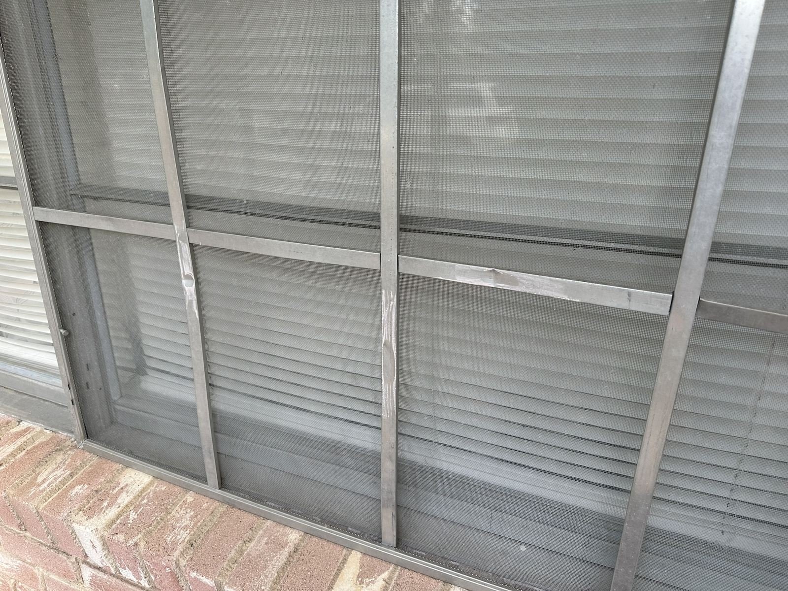 Torn and bent window screen mesh from hail
