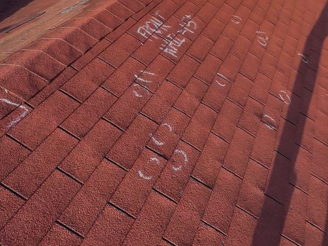 Hail hits circled in chalk on a red shingle roof