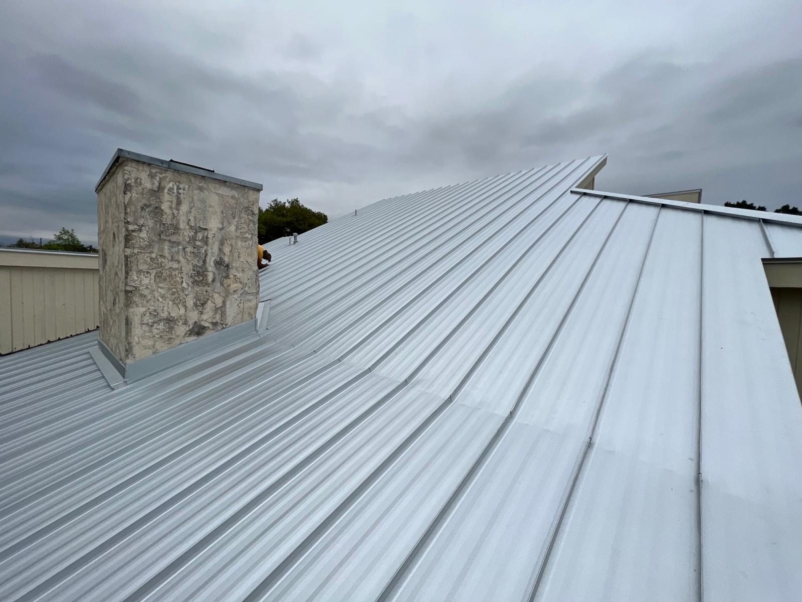 Metal roof installation detail around a stone chimney