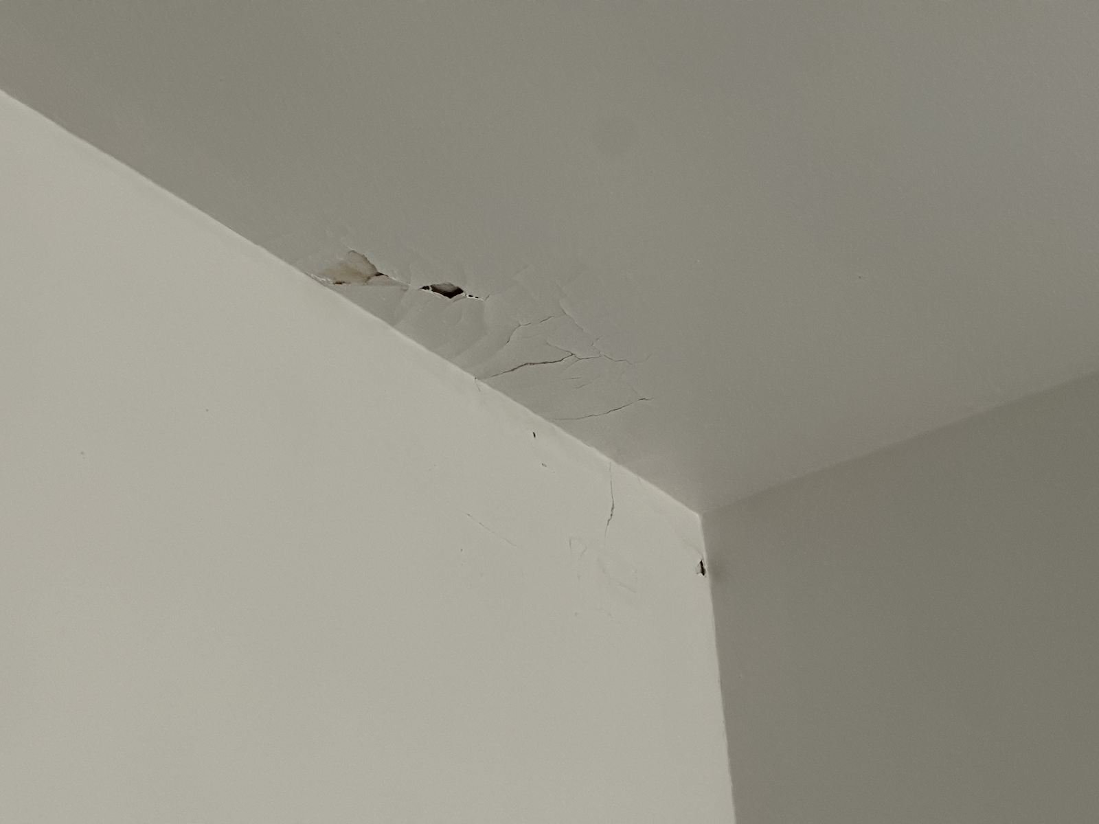 Cracked ceiling drywall in a corner from a roof leak