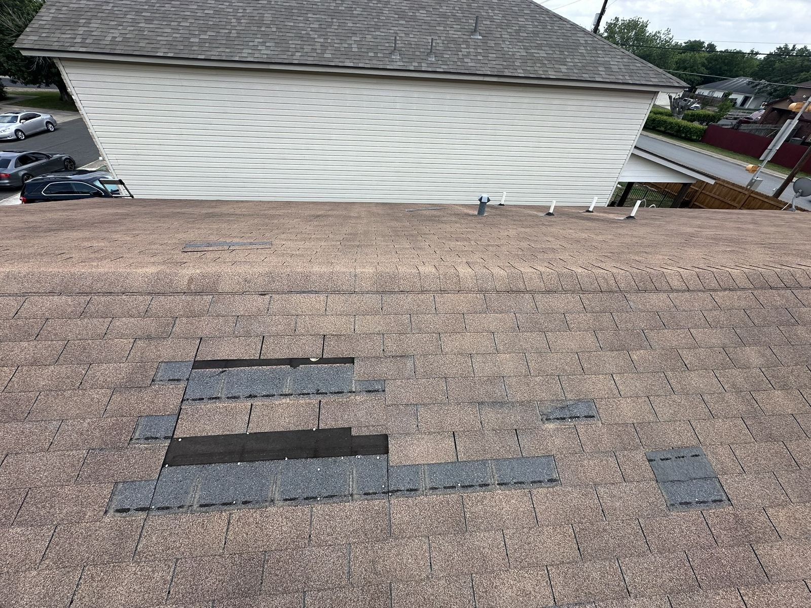 Roof section with wind-torn shingles removed down to the underlayment